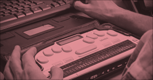 Persona utilitzant un lector braille al costat d'un teclat, símbol d'accessibilitat web