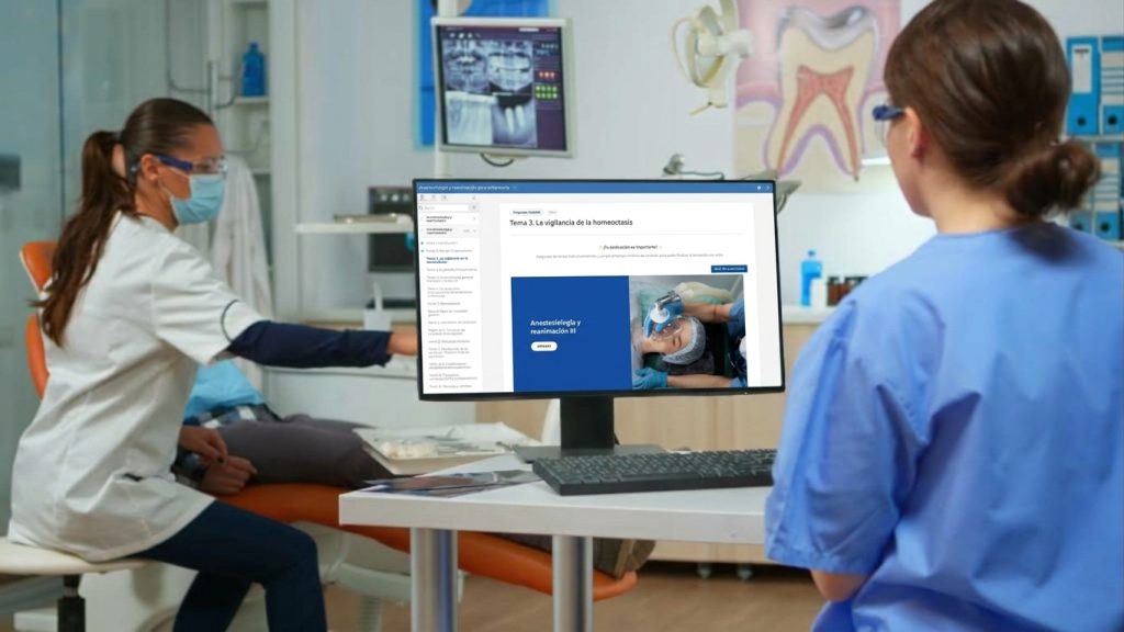 Una enfermera con uniforme azul sigue un curso de anestesiología y reanimación en el campus virtual de HDS, desde el ordenador de una clínica.